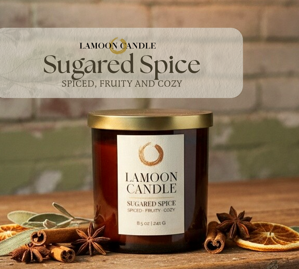 A jar candle labeled 'Lamoon Candle Sugared Spice' sits on a rustic wooden surface with cinnamon sticks, star anise, dried orange slices, and greenery. A translucent banner at the top reads 'LaMoon Candle Sugared Spice' and 'Spiced, fruity and cozy.