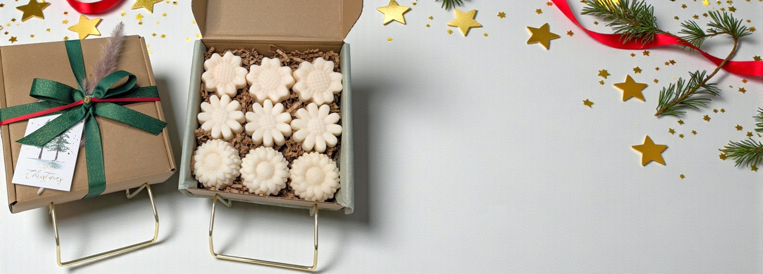 Box of flower shaped soy wax melts with a gift box and festive decorations on a white background.