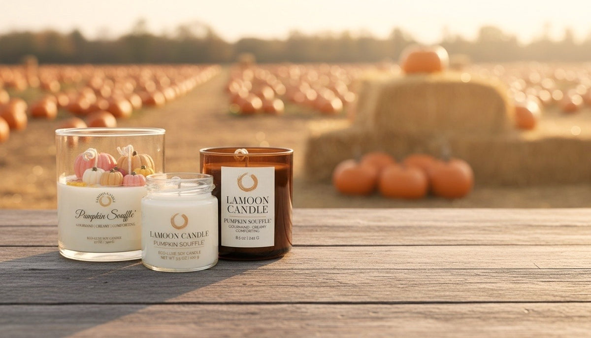Three LaMoon Candle products displayed on a wooden table outdoors at sunset, with a pumpkin field and hay bale blurred in the background. The set of candle labeled 'LAMOON CANDLE PUMPKIN SOFFLE''.